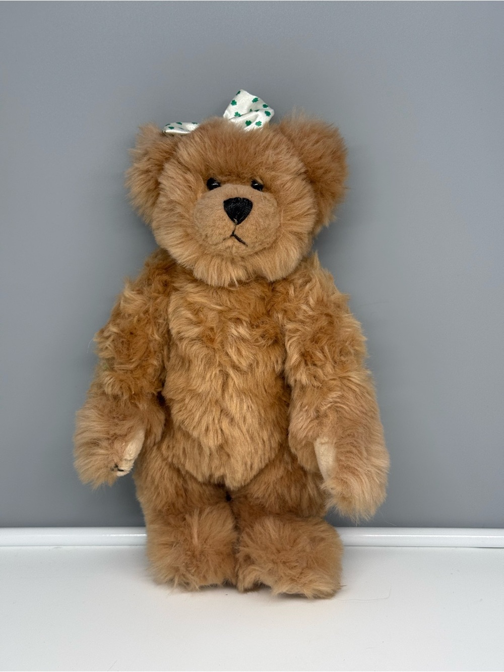 Traditional Craft Ltd. Irish Teddy Bear with a white bow with green shamrocks.